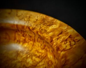 A close-up view of a handcrafted item featuring exquisite details in burl wood, karelian birch, and curly birch