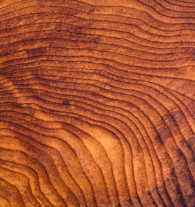 Close-up view of a redwood wood board showcasing its rich, reddish hues and straight grain. The wood is known for its durability, natural resistance to decay and insects, making it a popular choice for outdoor applications such as decking and fencing. Additionally, redwood is often used in crafting elegant furniture, adding a touch of timeless beauty to various spaces