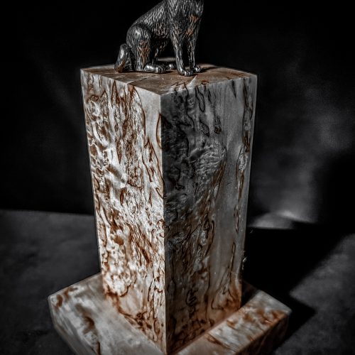 A handcrafted Karelian birch burl wood dog ashes keepsake urn adorned with a beautifully sculpted dog figure on the top.